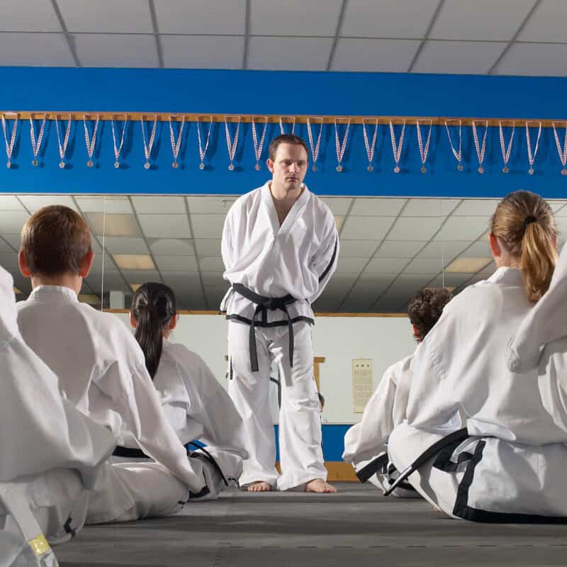 A martial arts instructor teaching a group of students in a dojo, demonstrating quality martial arts training and effective business management.