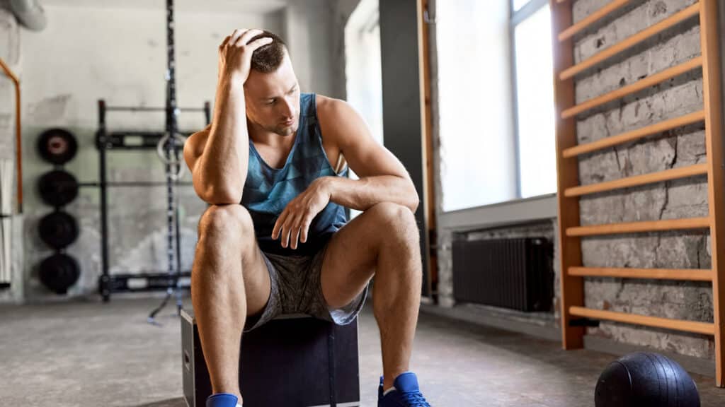 A man sits down at the gym after realising his membership payment is overdue.