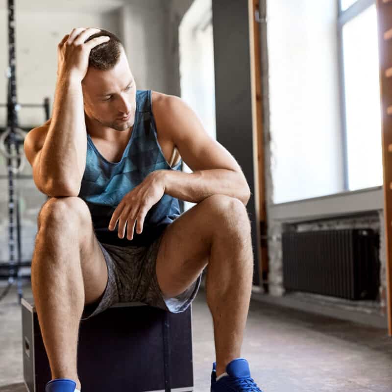 A man sits down at the gym after realising his membership payment is overdue.
