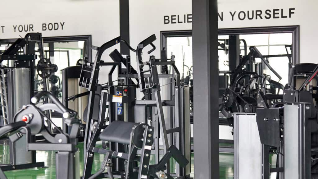 A gym with various exercise machines and motivational phrases on the walls, seamlessly managed with cutting-edge gym software.