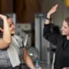 Two women smiling and giving each other a high-five at the gym, symbolising motivation, support, and community - key elements that help independent gyms stand out during the busy January rush.