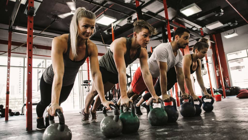 Group fitness class with a kettlebell workout, showcasing an active gym environment with high-quality amenities.