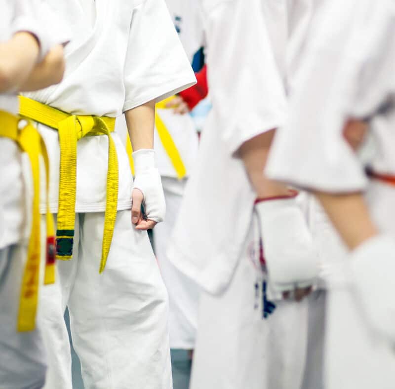 A group of martial arts students stand waiting for their first paid class to begin after successfully being converted from a free trial class.