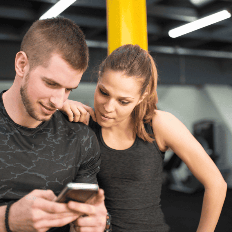 two people in the gym looking at a phone