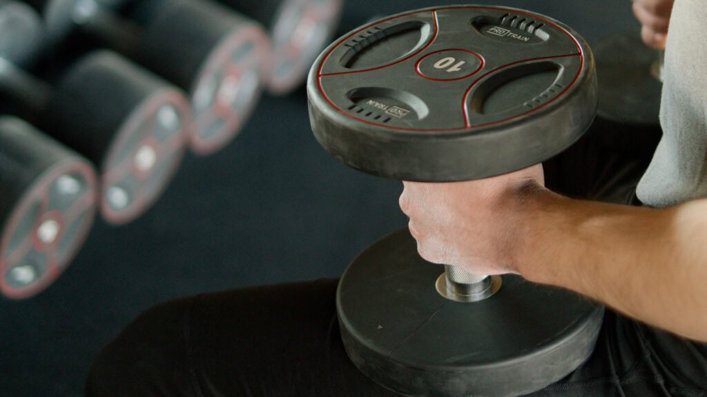 Person holds dumbbells after joining a new gym online instead of using WhatsApp.