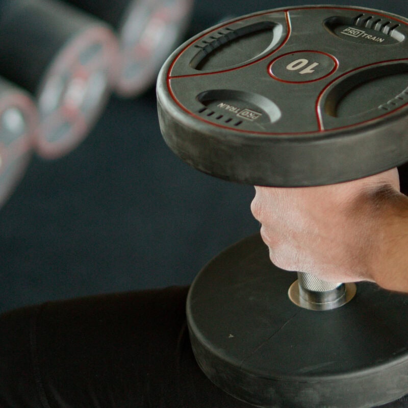 Person holds dumbbells after joining a new gym online instead of using WhatsApp.